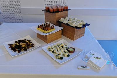 Plateau de buffet avec verrines, amuse-bouches variés et serviettes disposés sur une nappe blanche.