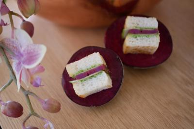 Deux mini-sandwichs garnis de légumes verts et d'oignons rouges, posés sur des tranches de betterave, avec une orchidée en…