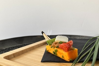 Traiteur Arômes et Sens Sèvres #3 Bouchée de polenta garnie de tomate confite, fromage et ciboulette, présentée sur un plateau en bois avec décoration…