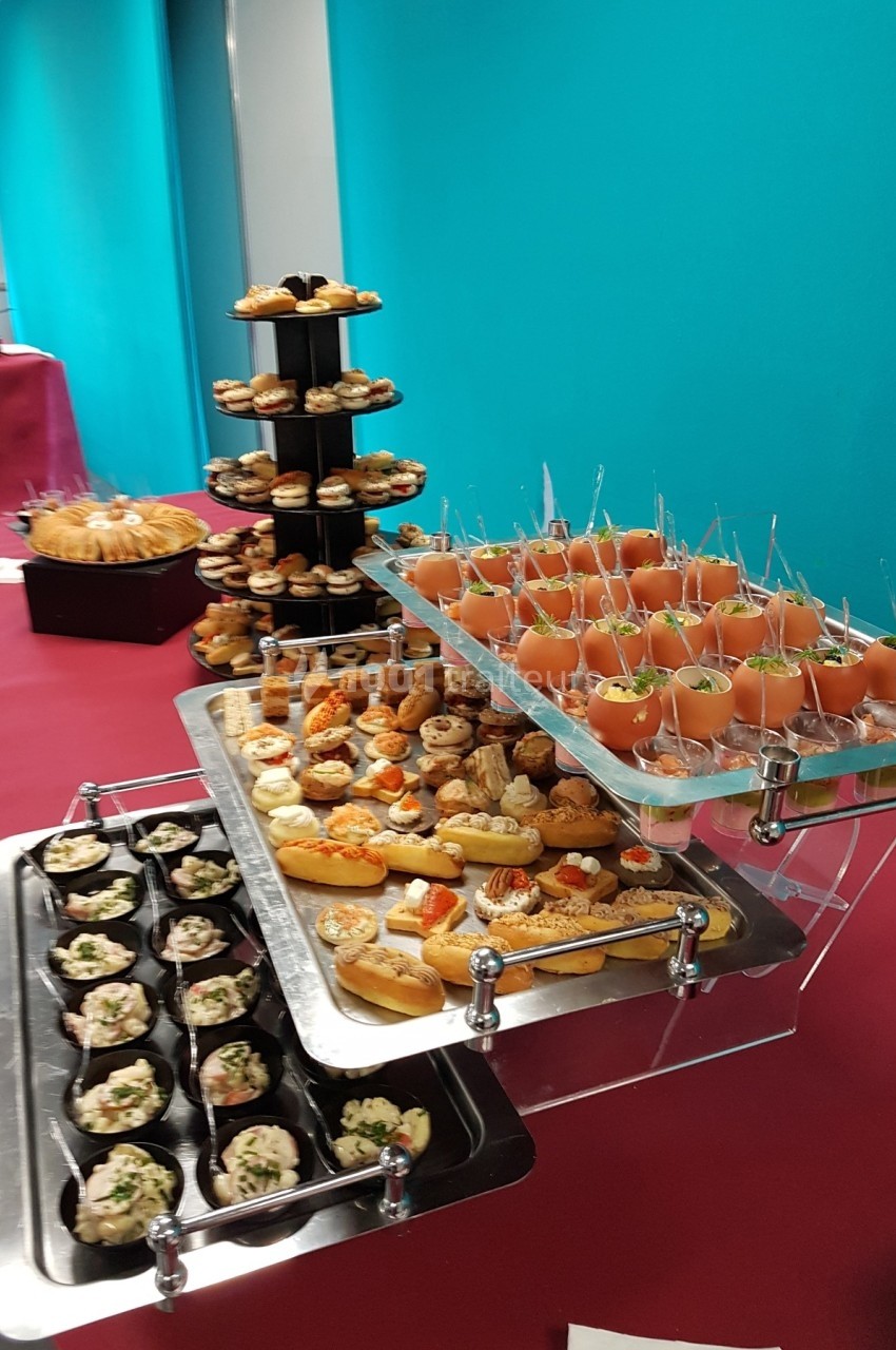 Buffet avec verrines, petits fours, pâtisseries et amuse-bouches disposés sur des plateaux et présentoirs.