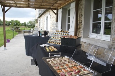 Traiteur Eclat des Saveurs Marles-en-Brie #3 Buffet en extérieur sous une pergola, avec plateaux de canapés, verrines et gâteaux disposés sur des nappes noires.