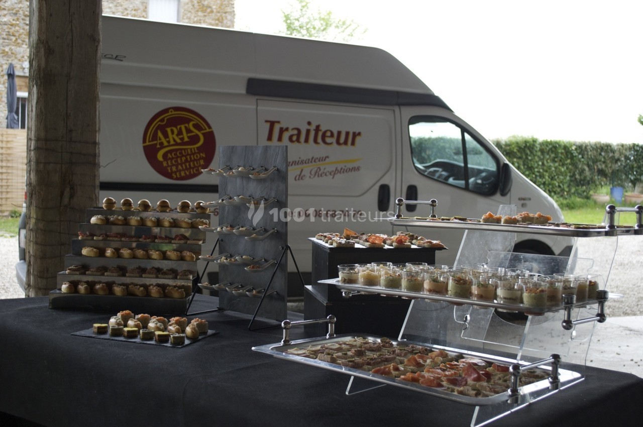 Traiteur Eclat des Saveurs Marles-en-Brie #1 Buffet de canapés et verrines disposé sur des présentoirs devant un véhicule de traiteur stationné.