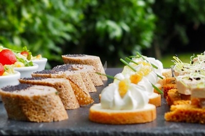 Traiteur France Evenement Traiteur Comines #2 Assortiment de canapés variés disposés sur une ardoise, avec un fond de verdure flou.