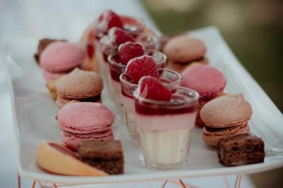 Plateau de desserts comprenant des macarons roses, verrines garnies de framboises et morceaux de gâteau au chocolat.