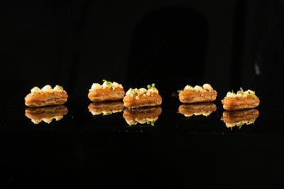 Traiteur Gaudefroy Receptions Ollioules #3 Quatre amuse-bouches disposés en ligne sur une surface noire réfléchissante, garnis de crème et de fines herbes.