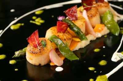 Traiteur Gaudefroy Receptions Ollioules #5 Noix de Saint-Jacques poêlées servies avec légumes colorés, purée et décorations culinaires sur une assiette noire.