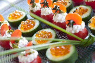 Assortiment de bouchées apéritives composées de tomates, concombres, fromage frais et œufs de poisson sur un plateau.