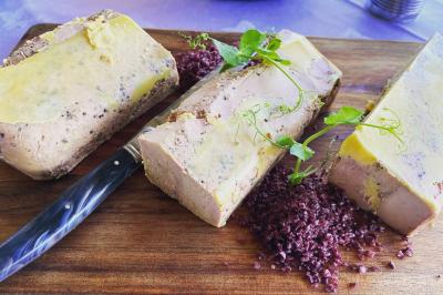 Traiteur Vironneau Evénementiel Galgon #3 Bloc de foie gras tranché sur une planche en bois, accompagné de sel noir et décoré de pousses vertes.