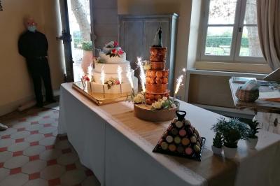 Table de desserts de mariage avec pièce montée, croquembouche, macarons et décorations florales, entourée de bougies…