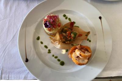 Assiette gastronomique composée de trois préparations raffinées, décorée de sauces et présentée sur une nappe blanche.