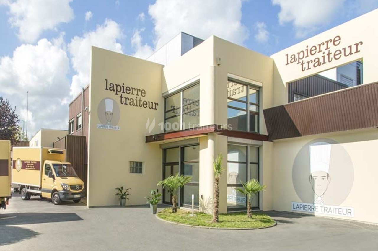 Façade d'un bâtiment moderne avec le logo ’Lapierre Traiteur’ et un camion de livraison stationné devant.