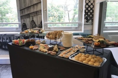 Buffet varié avec pains, amuse-bouches, fruits et desserts, disposé sur une table dans une salle lumineuse.