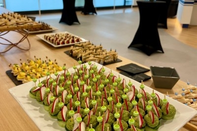 Plateau de bouchées apéritives garnies de mousse verte et de radis, disposé sur une table dans une salle de réception.