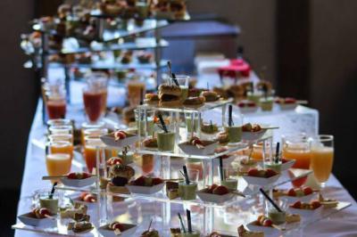 Buffet avec verrines, mini-sandwichs et jus de fruits disposés sur des présentoirs en verre et métal.