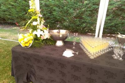 Table dressée avec une nappe noire, contenant une vasque, des verres alignés, un vase de citrons et une composition florale.