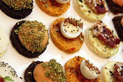 Assortiment de canapés variés avec garnitures colorées, présentés sur un plateau blanc.