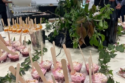 Traiteur Rousseau Traiteur Azay-le-Rideau #2 Desserts individuels roses avec cuillères en bois, disposés sur une table décorée de feuillage et de bouteilles de vin.
