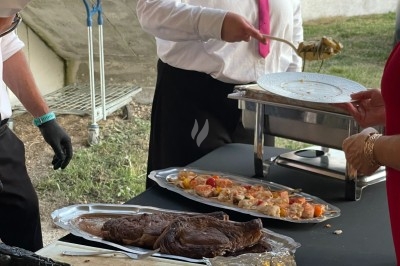 Traiteur Rousseau Traiteur Azay-le-Rideau #5 Serveurs en train de disposer des plats de viande et de brochettes sur une table lors d'un événement en extérieur.