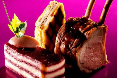 Assiette gastronomique composée d'un carré d'agneau, d'un millefeuille salé et d'une terrine sur fond rose.