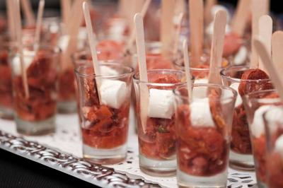 Verrines garnies de dés de fromage, morceaux de chorizo et sauce tomate, présentées avec des bâtonnets en bois.