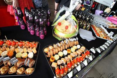 Plateaux de bouchées apéritives variées disposés sur une table, accompagnés de bouteilles et d'un panier cadeau.
