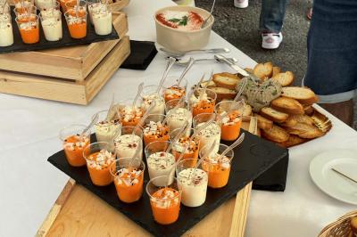 Verrines colorées disposées sur un plateau, accompagnées de pain grillé et d'une sauce en bol sur une table de buffet.