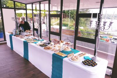 Traiteur Rubis Receptions Magny-le-Hongre #4 Buffet dressé dans une salle lumineuse avec vue sur un jardin et un plan d'eau, comprenant divers plats et décorations.