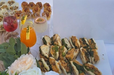 Traiteur Royal Events Traiteur et Tradition Saint-Cyr-en-Val #4 Plateau de mini-sandwichs garnis, accompagnés de cocktails colorés et de bouchées apéritives sur une table décorée.