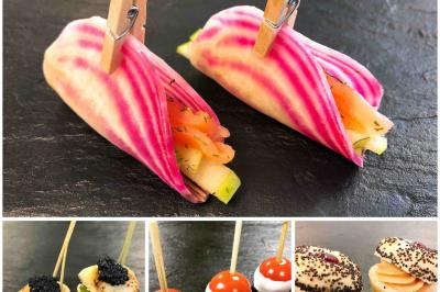 Assortiment de bouchées raffinées comprenant légumes, brochettes et mini-sandwichs sur ardoise noire.