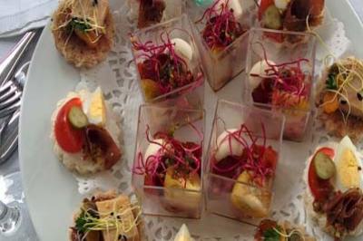 Assortiment de canapés et verrines colorés disposés sur un plateau rond, prêt à être servi.