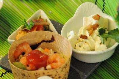 Assortiment de verrines et amuse-bouches avec crevettes, légumes et fromage, présenté sur un fond vert.