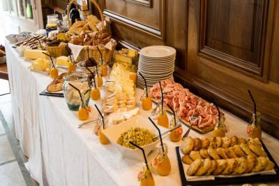 Table garnie de plats variés : charcuterie, fromages, pains, viennoiseries et jus, disposés pour un buffet.