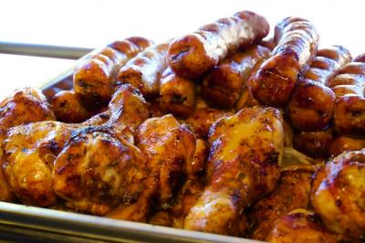 Poulet rôti et saucisses grillées disposés dans un plat en métal.