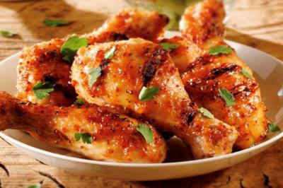 Morceaux de poulet grillés avec une marinade épicée, garnis de feuilles de persil dans une assiette blanche.