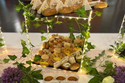 Plateau de buffet garni de sandwichs, roulés, muffins et autres amuse-bouches, décoré de guirlandes lumineuses et de…