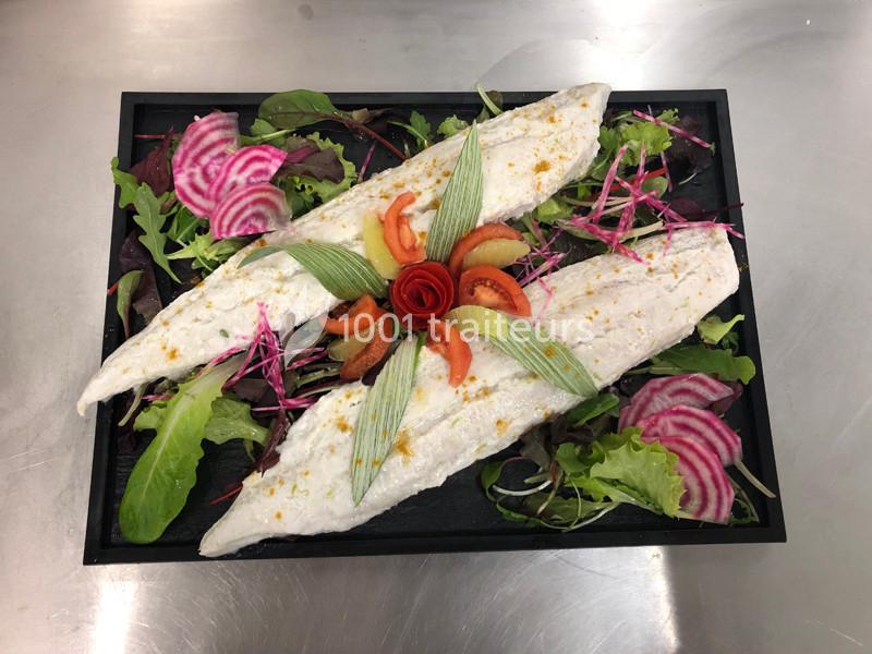 Filets de poisson cuits présentés sur un lit de salade verte, betteraves tranchées et garniture décorative.