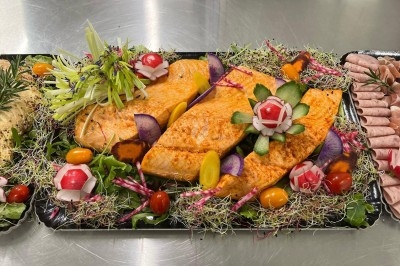 Plateau de saumon mariné garni de légumes frais, radis sculptés, tomates cerises et pousses décoratives.