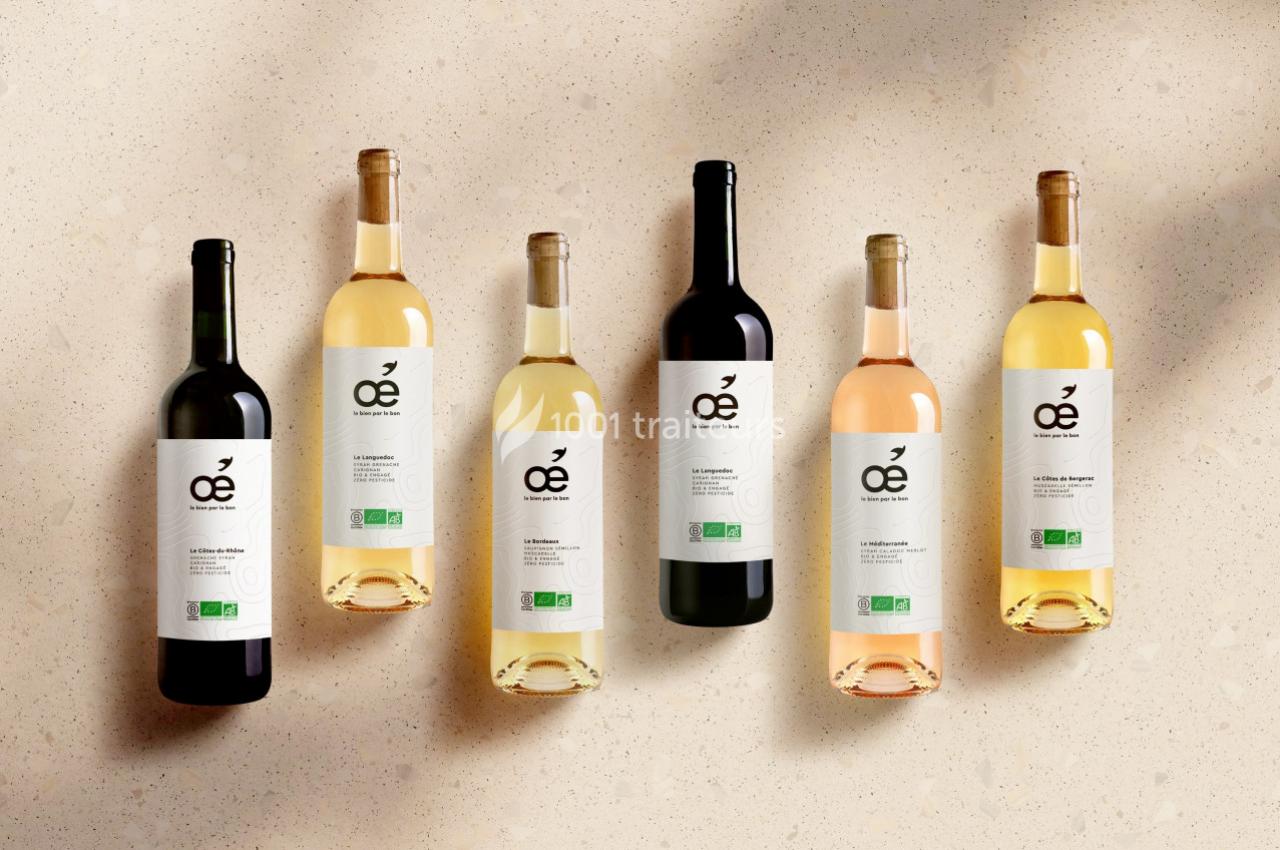Six bouteilles de vin bio aux étiquettes blanches alignées sur une surface beige avec une lumière douce.