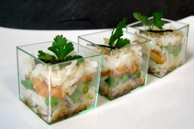 Verrines de riz garnies de saumon, petits pois et persil, présentées sur une assiette blanche.