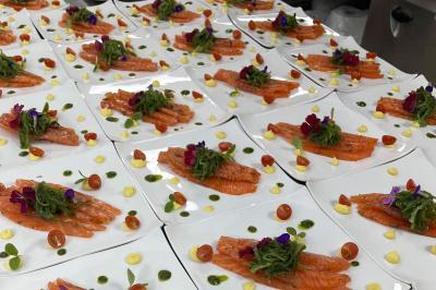 Assiettes de saumon fumé garnies de tomates cerises, algues, fleurs comestibles et sauces colorées.