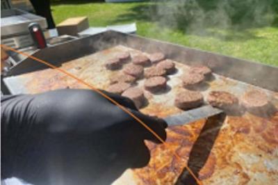 Traiteur Plancha Seclin #3 Cuisson de plusieurs steaks hachés sur une plaque chauffante, une main gantée tenant une spatule.