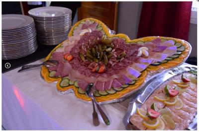 Traiteur Plancha Seclin #5 Plateau de charcuterie en forme de papillon, décoré de légumes, cornichons et fraises, avec assiettes empilées à côté.