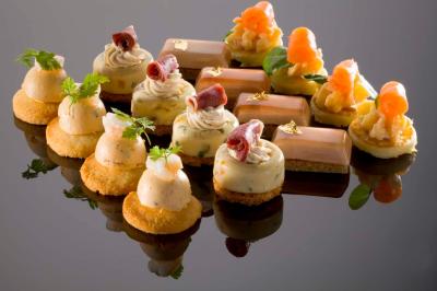 Assortiment de bouchées apéritives raffinées disposées sur une surface réfléchissante.