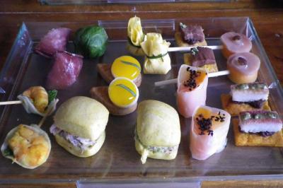 Plateau de bouchées apéritives variées comprenant sushis, mini-sandwichs et amuse-bouches colorés.