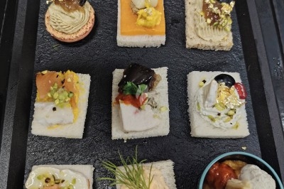 Plateau de canapés variés et colorés accompagnés de petites verrines, présenté sur un plateau noir.