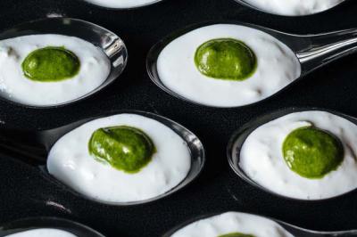 Traiteur Profumo Traiteur Italien Paris #3 Cuillères contenant une mousse blanche garnie d'une touche de sauce verte, disposées sur une surface noire.