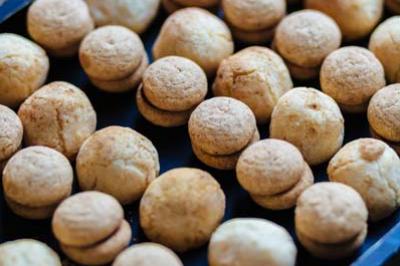 Plateaux remplis de petits biscuits dorés ronds alignés sur une surface sombre.