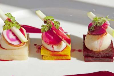 Assiette gastronomique avec trois bouchées colorées à base de légumes, noix de Saint-Jacques et garnitures fines.