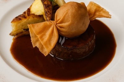 Plat gastronomique composé d'une viande nappée de sauce, accompagné d'un croustillant et de légumes rôtis.