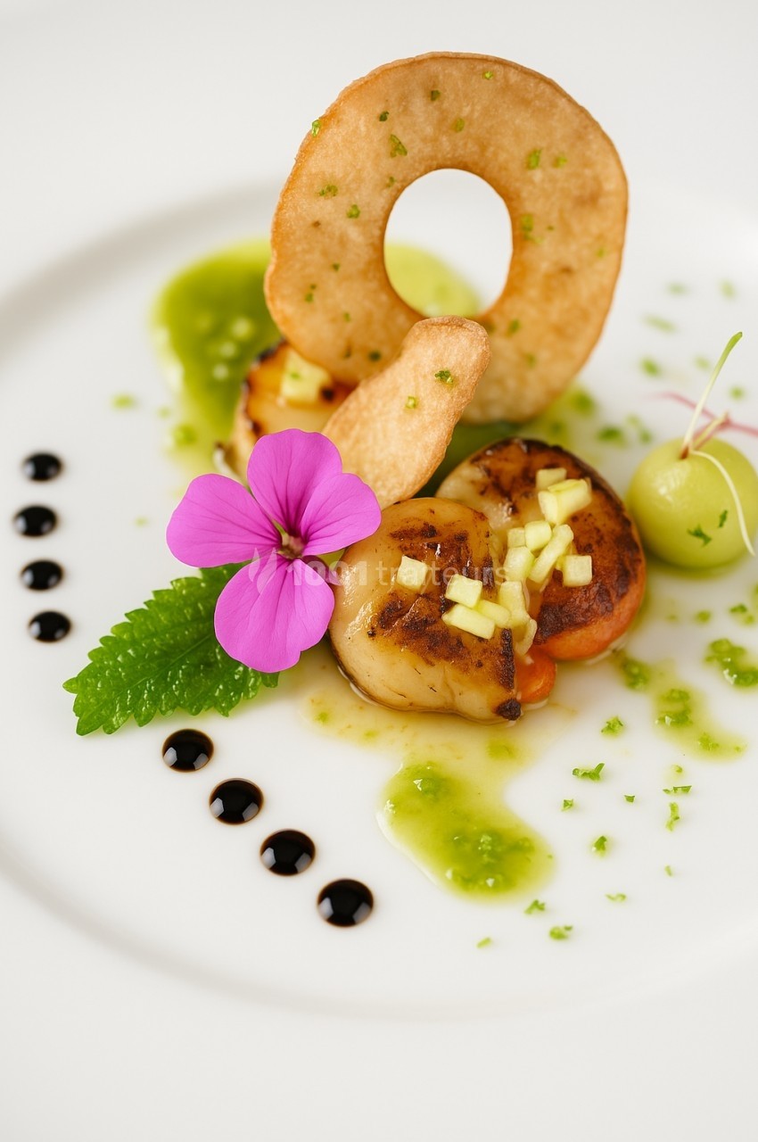 Assiette gastronomique avec noix de Saint-Jacques, garniture de pomme, fleur comestible et sauce verte décorative.